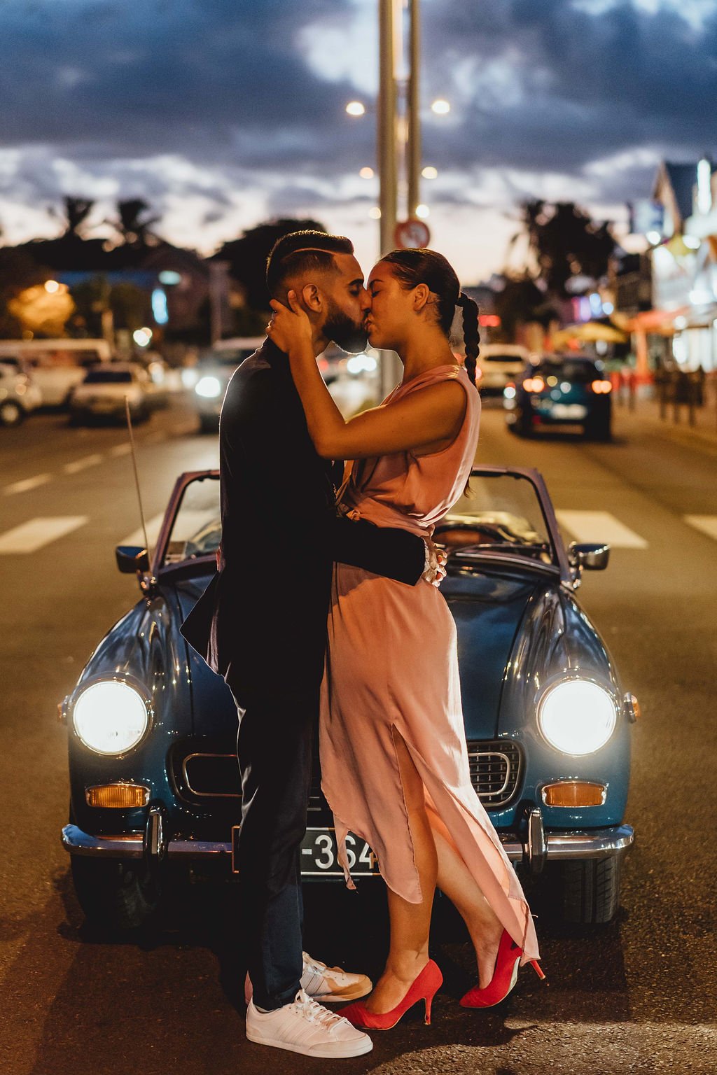 Couple qui s'embrasse devant une voiture au milieu de la route